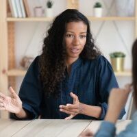 Close up confident african american businesswoman explaining new responsibilities to female applicant. Attractive young diverse woman hr manager talking and introduction company to job seeker.